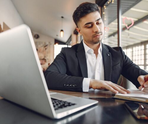 Mann schreibt Notizen während Online Führungsseminar