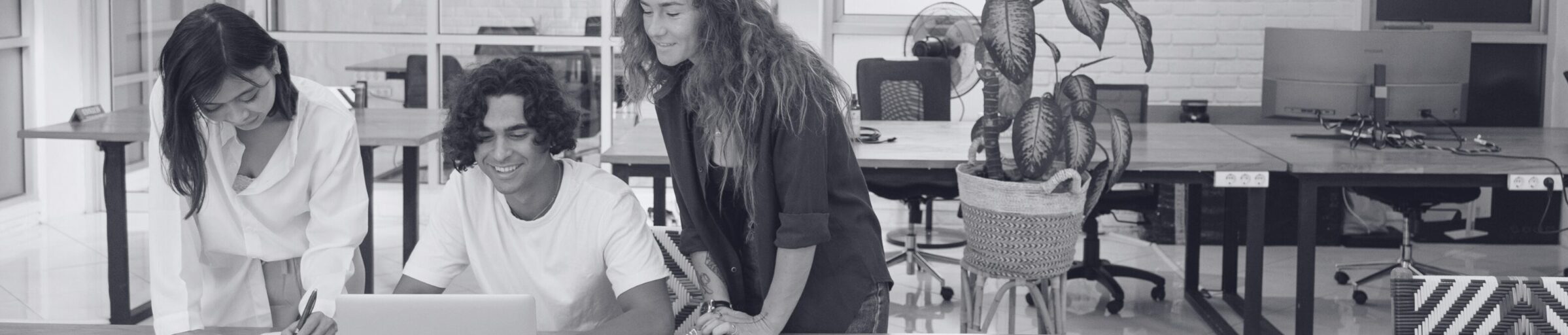 2 Frauen und 1 Mann sitzen vor Laptop und lachen