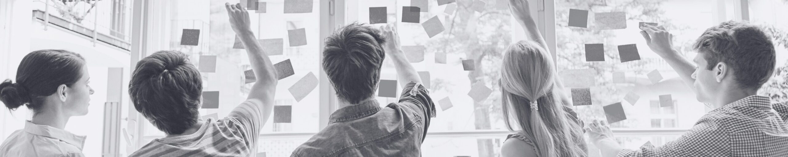 Workshop Teilnehmer kleben Post-Its auf Glasscheibe
