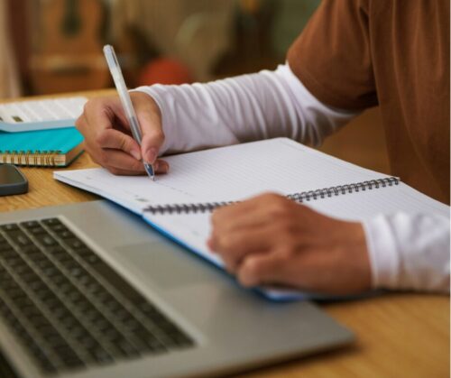 Hand schreibt etwas auf Notizbuch