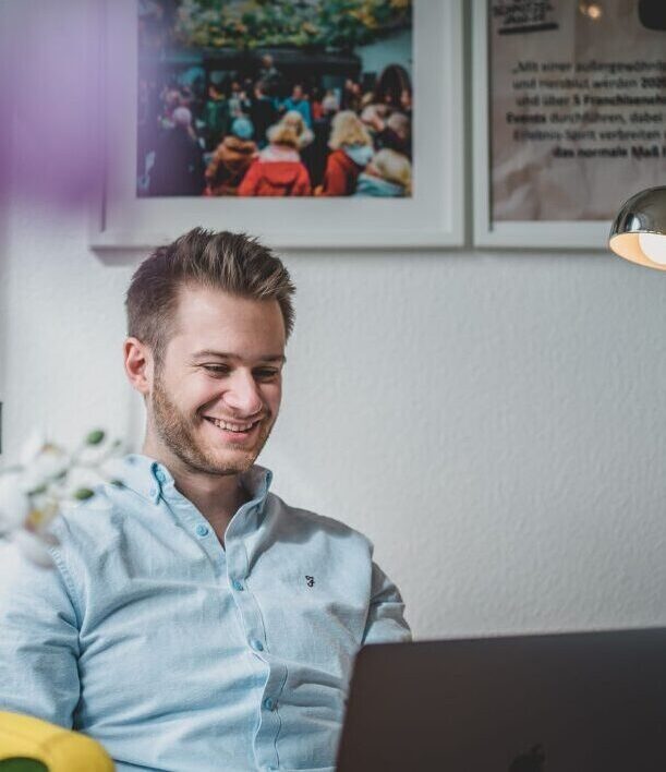 Mann lacht und schaut auf Laptop